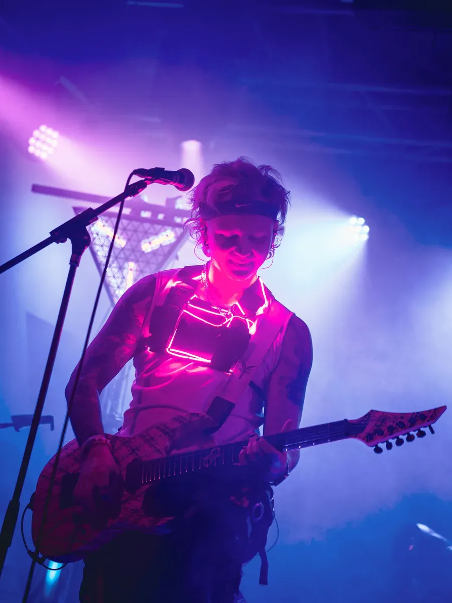 Bassist mit pink leuchtender LED-Weste und Gitarre im Nebel