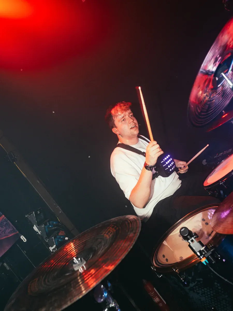 Drummer spielt intensiv unter rotem Scheinwerferlicht