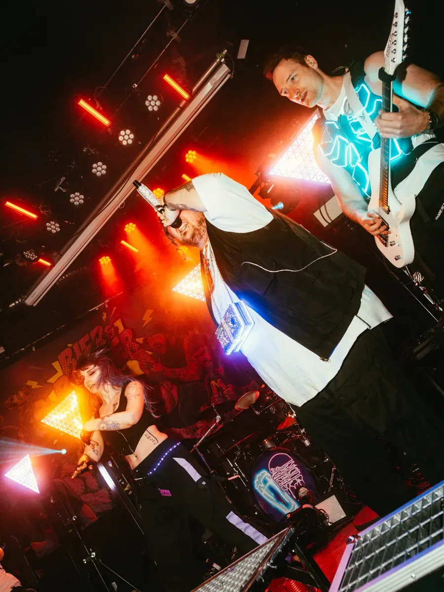 Saenger und Gitarrist performen unter roten und cyan Lichtern