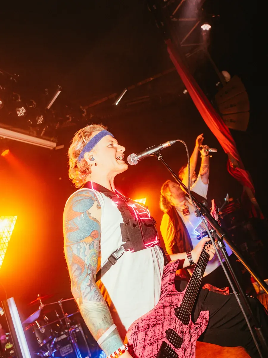 Bassist singt leidenschaftlich am Mikrofon mit pinker Gitarre