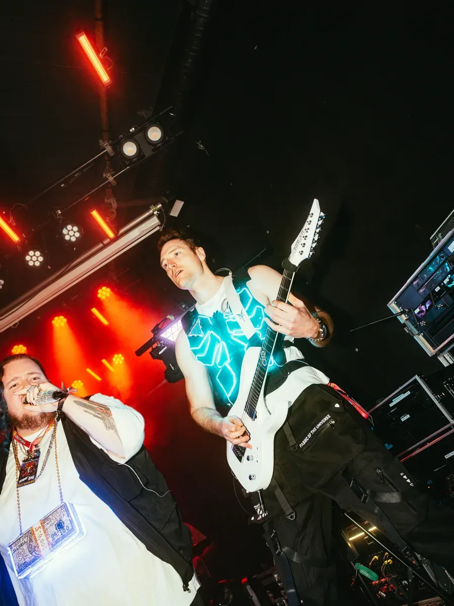 Saenger singt waehrend Gitarrist mit LED-Outfit daneben spielt